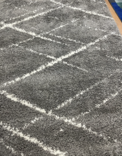 View of the gray rug with white lines making geometric overlapping diamonds.