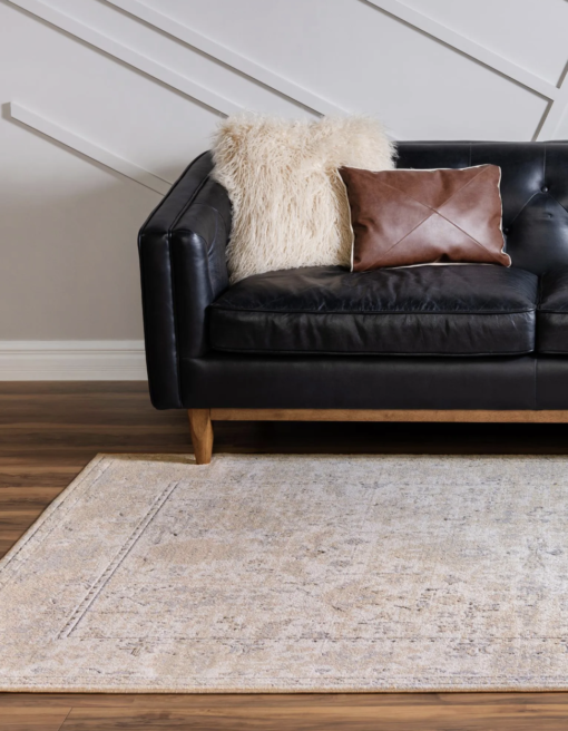 Rug on a brown wooden floor with black sofa and white walls