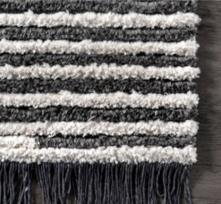 Gray and beige alternating stripes from rug with gray tassle fringe.