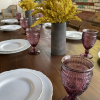 Wooden farmtable with white plates, plum matching goblets and goldenrod plant in a gray ceramic vase