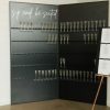 Black Champagne Wall with two panels. Each row holds 13 glasses, with 5 rows per panel. At the top of 1 panel, "sip and be seated" in script white letters.