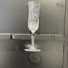 One crystal etched glass champagne flute held by the stem. Black background.