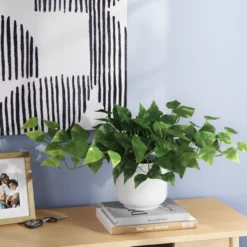 Plant sitting on books next to art and a frame
