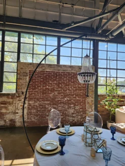 Gala Chandelier freestanding black chandelier over styled table setting with ghost chairs at brick venue