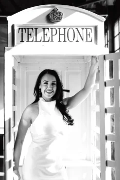 Pierre Phone Booth model posing inside white vintage British telephone booth at event