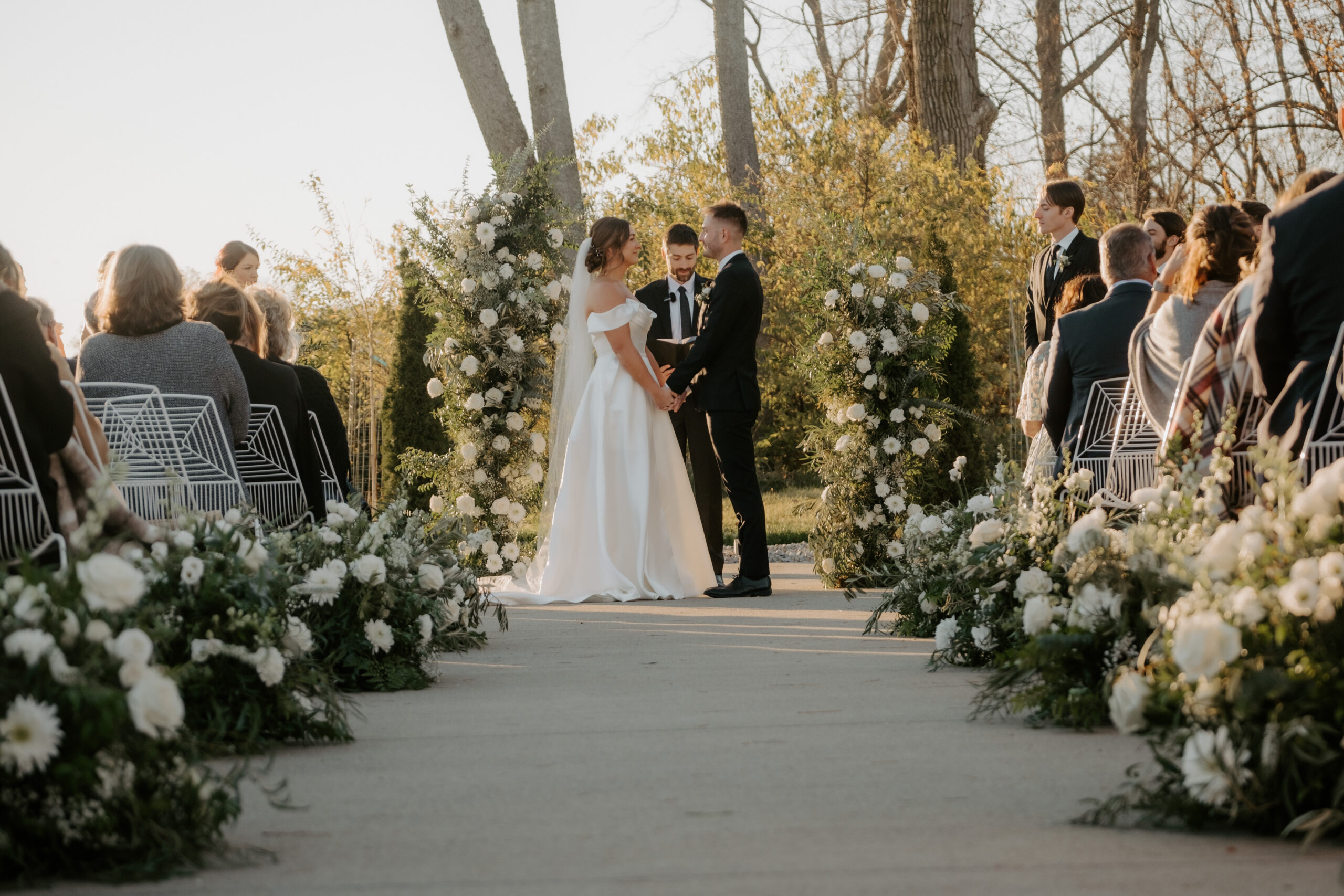 Modern White Wire Metal Chairs lining a wedding ceremony aisle