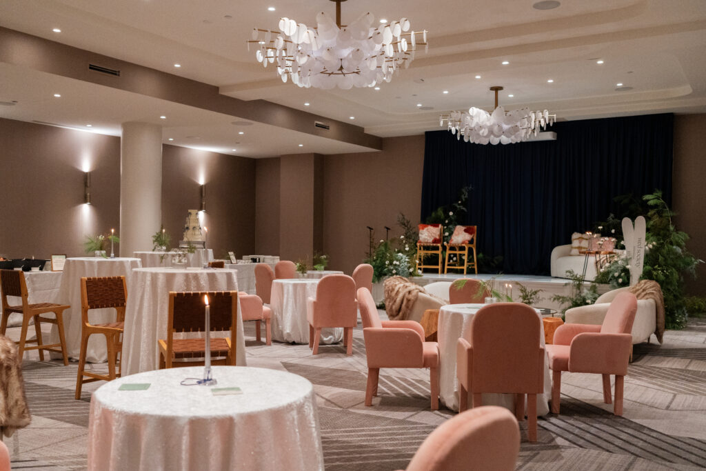 InterContinental Indianapolis ballroom arranged with a speaking stage, lounge furniture, pink guest chairs, and cocktail tables
