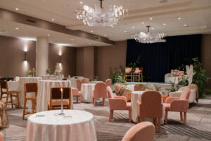 InterContinental Indianapolis ballroom arranged with a speaking stage, lounge furniture, pink guest chairs, and cocktail tables