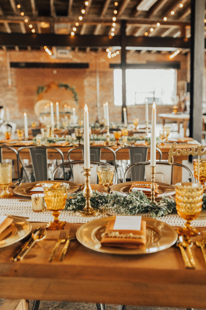 Amber goblets and large brass candlesticks on a fall wedding reception table at INDUSTRY Indianapolis
