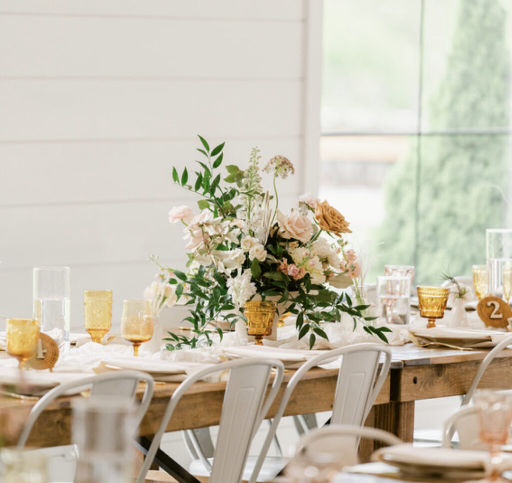 Amber goblets repeated across a wood wedding reception table at The Wilds near Bloomington, Indiana