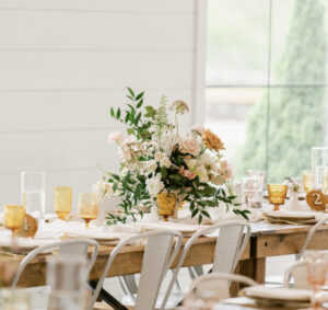 Amber goblets repeated across a wood wedding reception table at The Wilds near Bloomington, Indiana