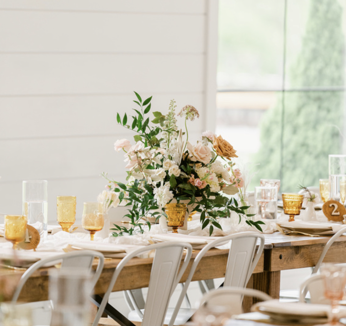 Amber goblets repeated across a wood wedding reception table at The Wilds