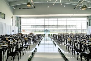 Kingston Farmtables and Dark Resin Vineyard Cross Back Chairs set for a wedding reception inside Beck's Hangar in Zionsville, Indiana.