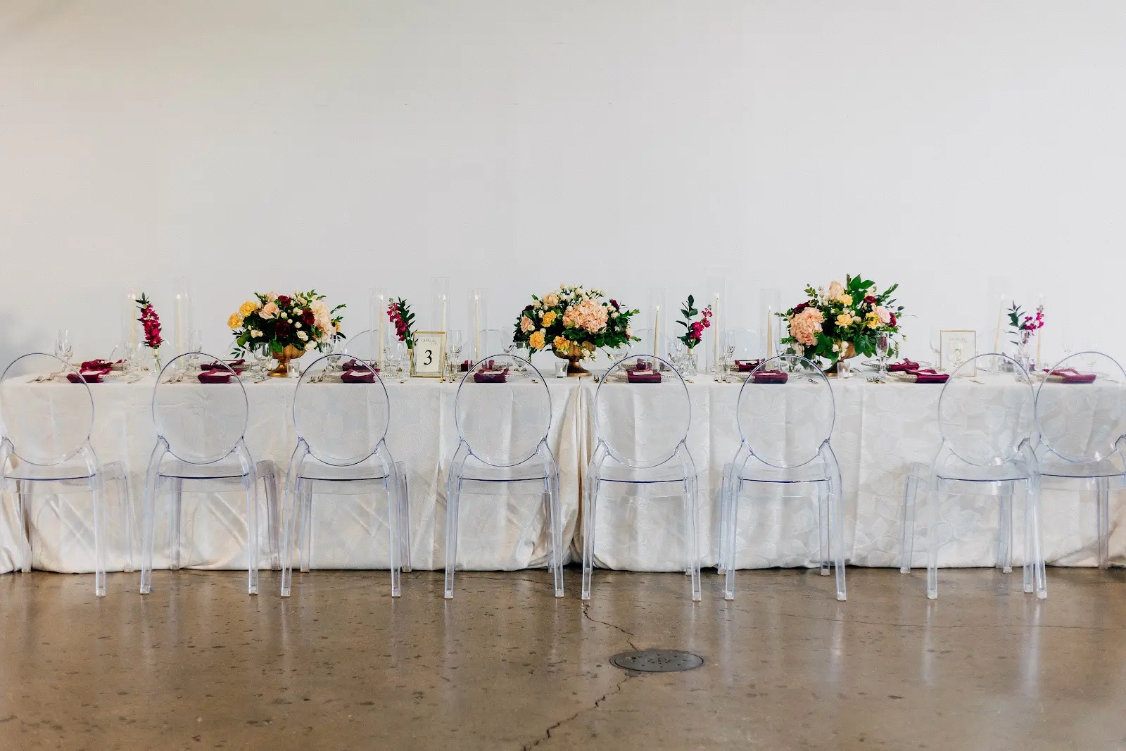 Ghost Chairs around a long wedding reception table with florals at VV Showroom in Indianapolis