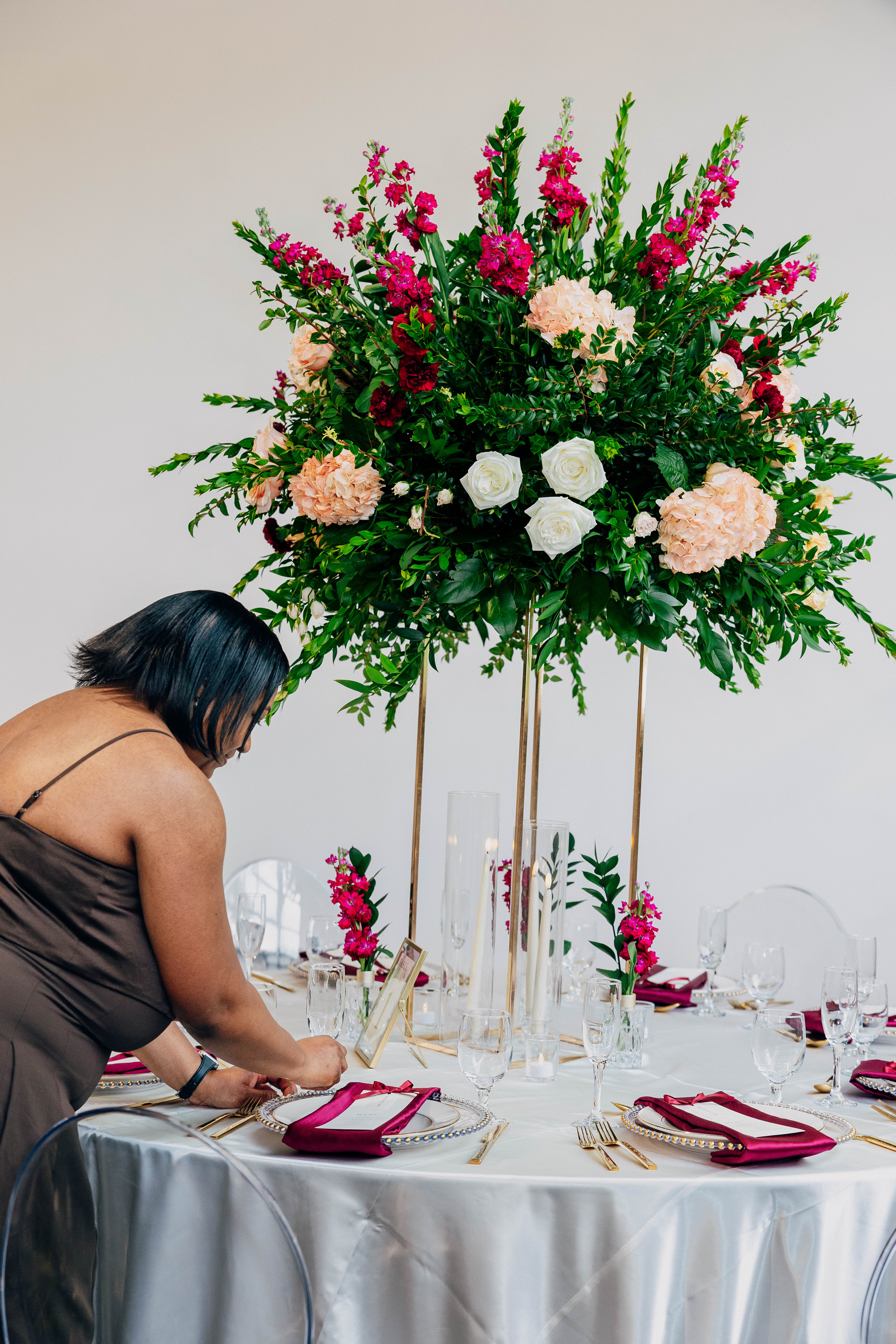 LoveLight Events team member arranging wedding florals and place settings during setup at VV Showroom in Indianapolis