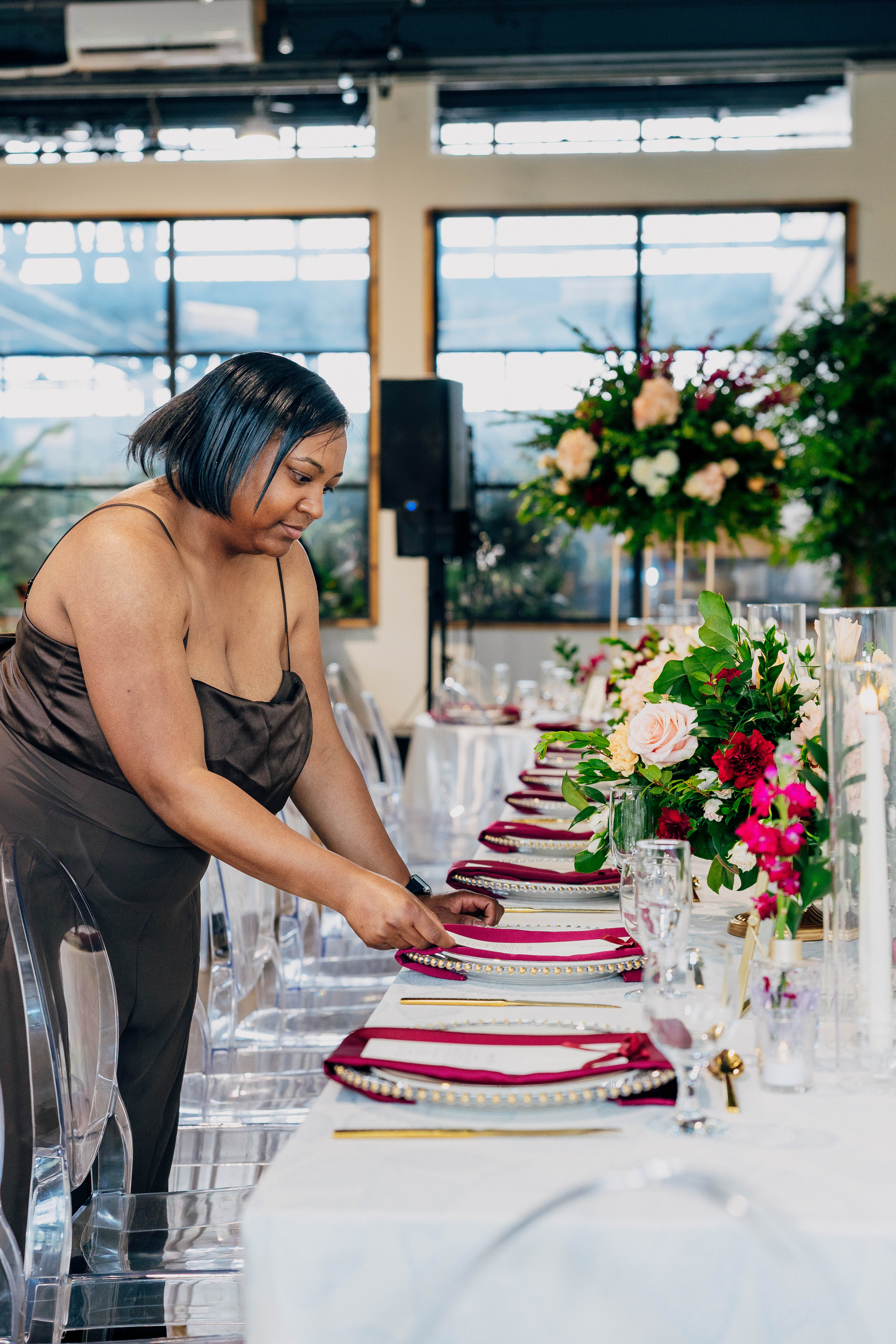 LoveLight Events team member placing a wedding setting beside reception florals at VV Showroom in Indianapolis