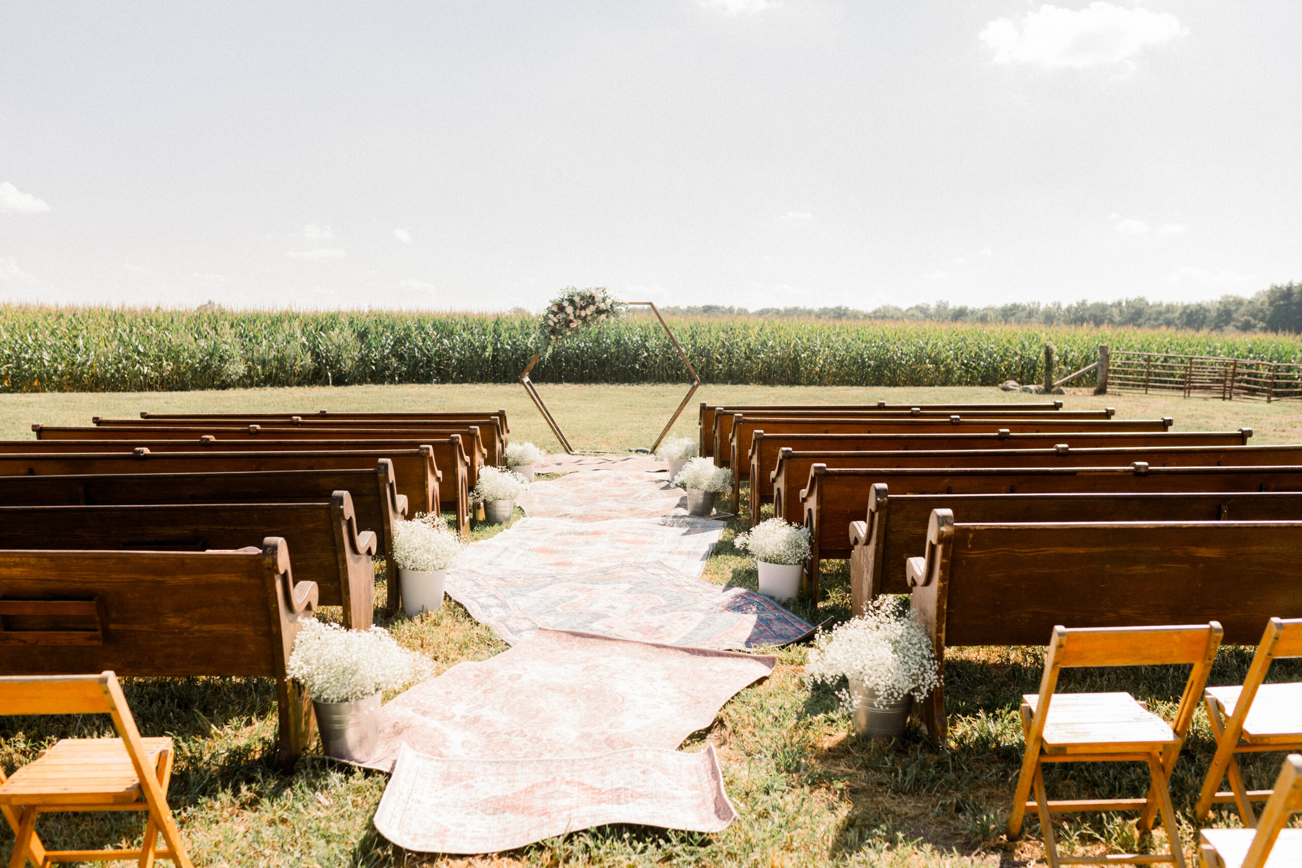 Violet Vintage Rentals church pews lining an outdoor wedding aisle at The Barn in Zionsville