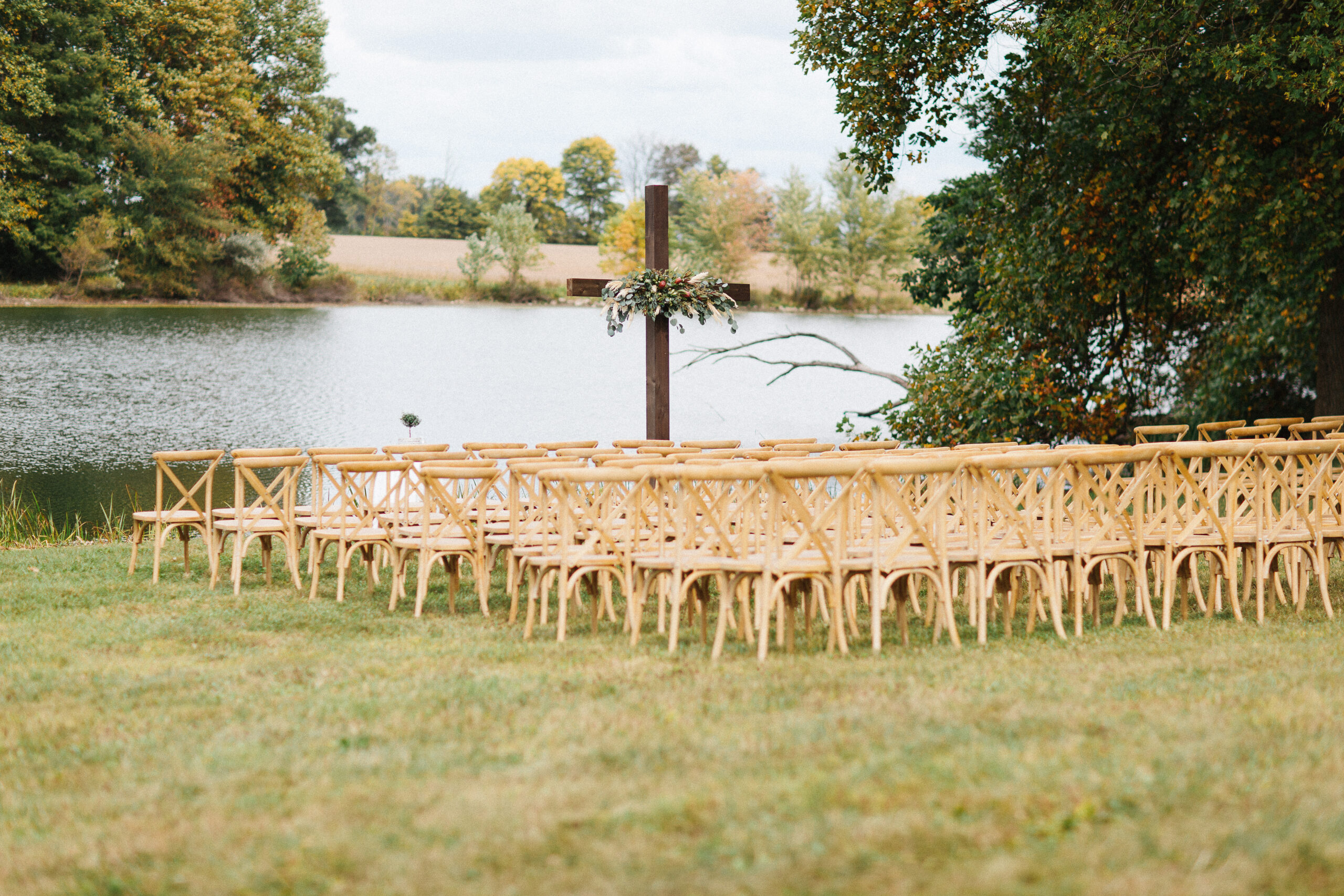 Light Wood Vineyard Cross Back Chairs arranged for an outdoor wedding ceremony